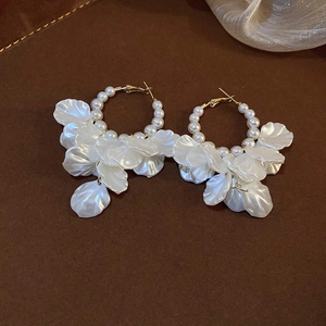 Detail of gold hoop earrings with white pearls and hanging translucent flower petals