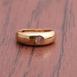 Close-up of a gold solitaire ring with a round zircon on a dark wood background