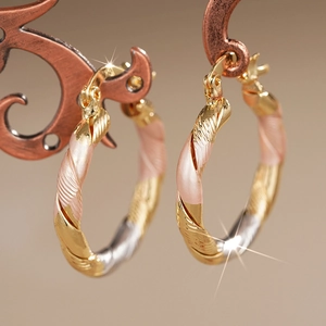 Macro view of tricolor gold twisted hoop earrings with textured finish on display
