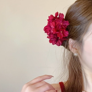 Detailed close-up of a burgundy fabric floral hair pin with realistic silk petals