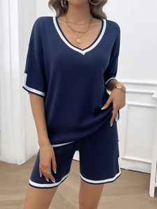 Detail of navy knit lounge set featuring white stripe trim on V-neck and hem