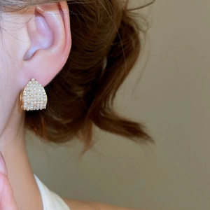 Detailed close-up of a vintage-style gold earring with sparkling pearls and zircon accents