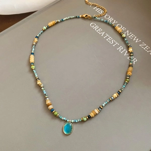 Macro shot of blue beaded necklace with oval opal pendant on a grey book background