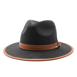 Détail du chapeau de paille noir avec bordure en cuir marron et boucles à rivets dorés