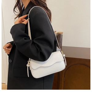 Minimalist white leather crossbody bag shown on a shoulder with a chic black blazer