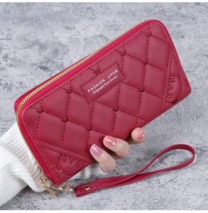 Detail of red quilted leather clutch wallet with bear embossing and gold zipper strap