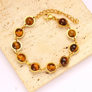 Detail of round tiger eye stone bracelet with golden metal chain and lobster clasp