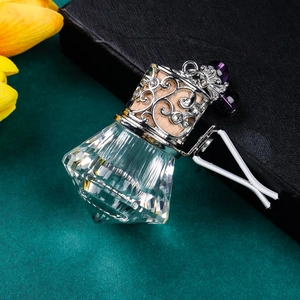 Close-up of diamond-cut crystal glass perfume bottle with purple bead for car vents