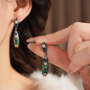 Détail de boucles d'oreilles vintage en forme de larme avec zircons vert émeraude et bleu