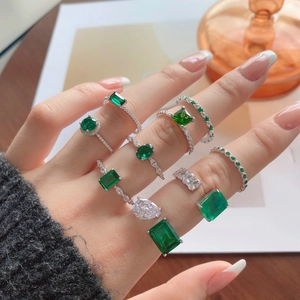 Close-up of stacked S925 silver rings with emerald green stones and zircon accents