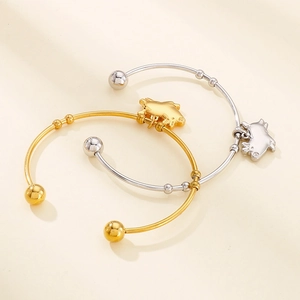 Détail de bracelets dorés et argentés avec pendentif cochon et finition métal poli