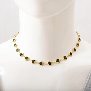 Detailed view of vintage gold necklace with heart-shaped links and green emerald gems