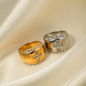 Macro detail of gold and silver cross rings with crystals on beige satin fabric