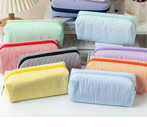 Detailed stack of multi-color seersucker pencil cases with striped textures and metal zippers