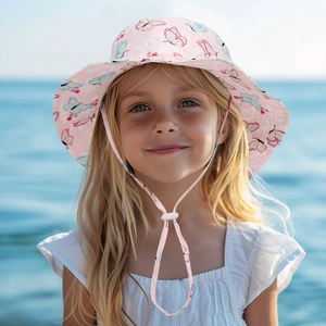 Close-up of pink sun hat with butterfly patterns and adjustable strap on beach background