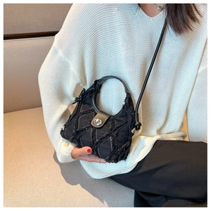 Close-up of quilted black crossbody bag with raw edges and silver metallic lock detail