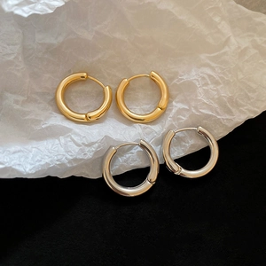 Close-up of gold and silver polished metal hoop earrings with mirror finish on white paper