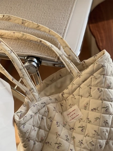 Détail du sac cabas matelassé en velours côtelé fleuri avec étiquette brodée élégante
