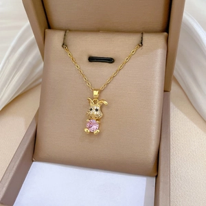 Close-up of golden bunny necklace with pavé zircons and a round pink gemstone inlay