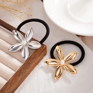 Detail of floral hair ties with gold and silver metal petals and pearls on wooden tray