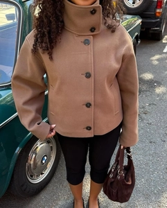 Detail of short brown wool jacket with stand-up collar and buttons on model