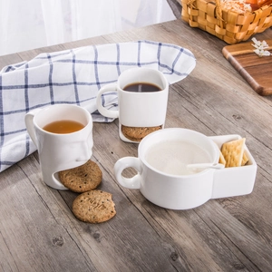 White ceramic mugs with built-in biscuit holders on a rustic wooden table setup