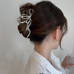 Detail view of a silver y2k metal shark hair claw clip with pearls in a stylish bow shape