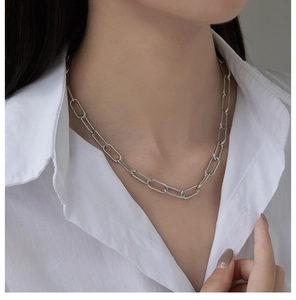 Detail of silver rectangle paperclip link chain necklace worn with a white shirt
