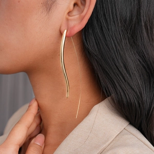 Close-up of elegant 18K gold plated long curved drop earrings on a fashion model