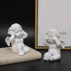 Set van twee vintage witte hars engelbeelden op decoratieve boekachtergrond