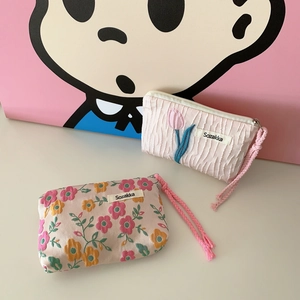 Detail view of pink pleated lipstick pouch and floral coin purse with woven drawstring