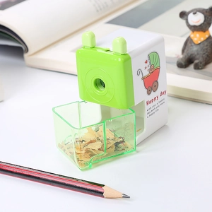 Cartoon hand-crank pencil sharpener in white and green with a transparent waste tray