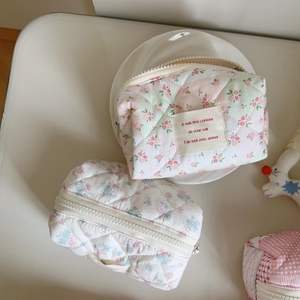 Quilted floral cotton cosmetic bag with zipper and handle on a white desk