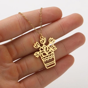 Vue rapprochée d'un collier doré avec pendentif plante miniature en acier inoxydable
