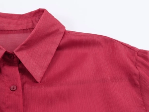 Gros plan sur chemise rouge en mousseline avec col à revers et boutons détaillés