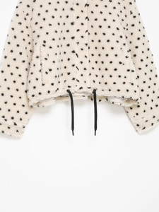 Détail de la veste en polaire blanche à pois avec cordon de serrage réglable en bas