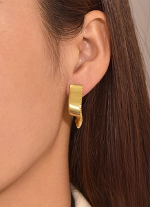 Detail of geometric wave gold earrings with micro-inlaid zircons worn by a model
