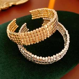 Gros plan de bracelets perlés multicouches or et argent sur support en velours vert