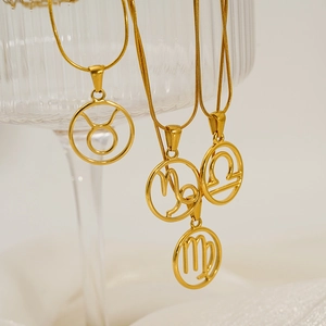 Polished gold 12 zodiac hollow pendant necklaces on a minimalist glass display