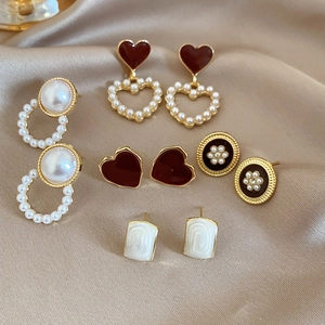 Macro detail of geometric pearl and diamond earrings set on luxury champagne silk fabric