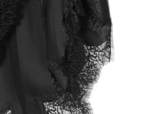 Detail view of smooth black satin fabric and delicate lace trim on the dress