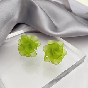 Macro shot of fruit green frosted flower stud earrings on silk background