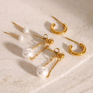 Three-piece stainless steel earring set with gold hoops and faux pearl pendants on stone