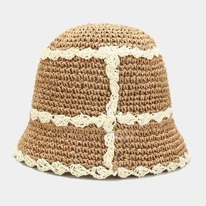 Detail of brown straw bucket hat featuring white crochet lace and wavy grid textures