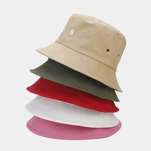 Détail de chapeaux bobs empilés de plusieurs couleurs avec broderie N et œillets en métal
