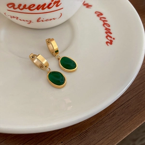 Detail shot of vintage titanium earrings with emerald green stone on white ceramic