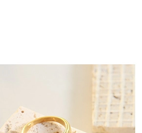 Macro detail of luxury gold ring placed on natural textured beige stone surface
