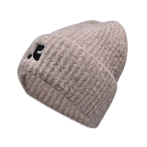 Close-up of beige knit beanie featuring detailed black puppy embroidery on thick ribbed cuff