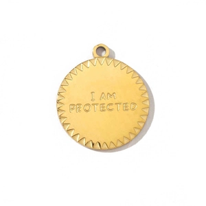 Vue macro du pendentif doré avec gravure I AM PROTECTED et détails de bordure dentelée
