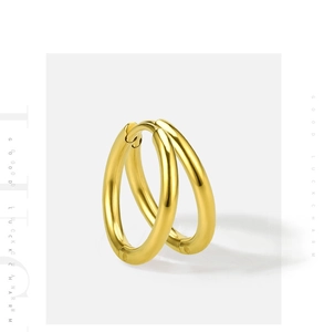 Detail of polished gold hoop earrings in stainless steel with Good Luck Charm text